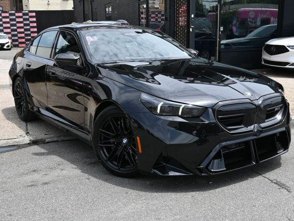 BMW M5 Hybrid parked in an urban setting at night, with LED headlights illuminated.