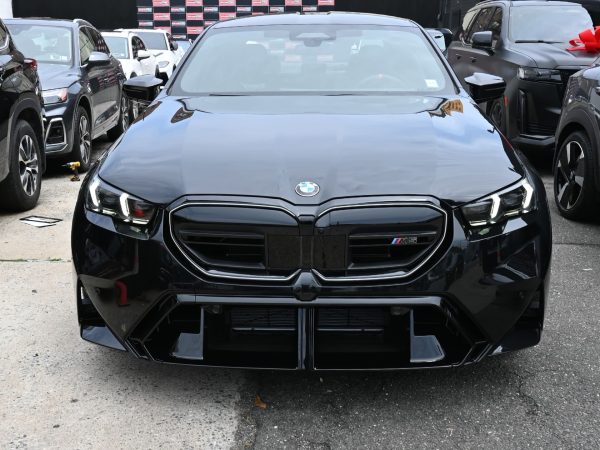 BMW M5 Hybrid parked in an urban setting at night, with LED headlights illuminated.