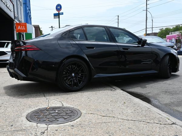- BMW M5 Hybrid driving through city streets at dusk, showcasing its sleek design.
