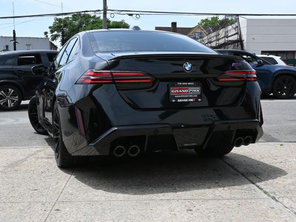 Rear three-quarter view of the BMW M5 Hybrid, emphasizing its muscular stance and LED taillights.