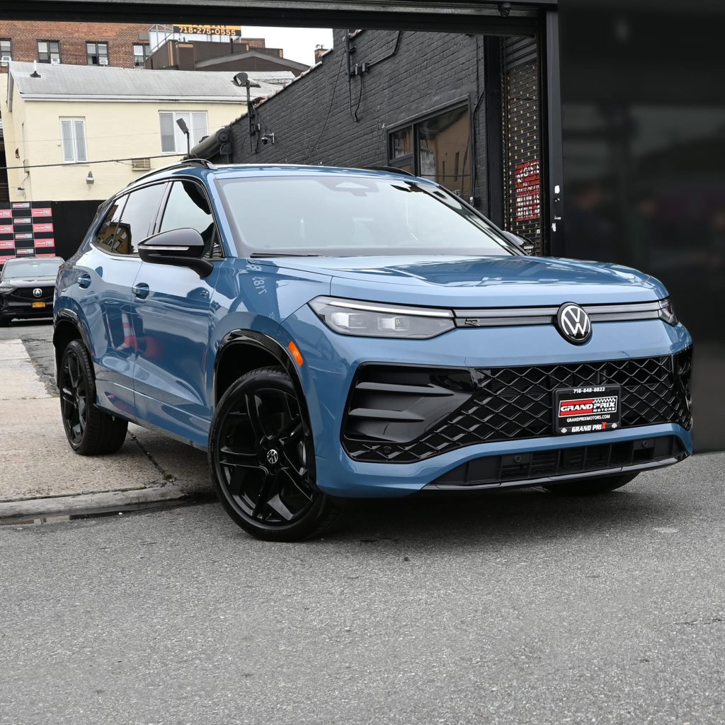 Front view of the 2025 Volkswagen Tiguan featuring bold grille, LED headlights, and illuminated VW logo, parked outside Grand Prix Motors in Brooklyn