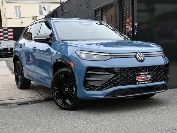 Front view of the 2025 Volkswagen Tiguan featuring bold grille, LED headlights, and illuminated VW logo, parked outside Grand Prix Motors in Brooklyn