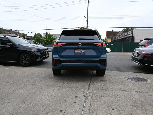 Rear view of the 2025 Tiguan in motion, demonstrating LED taillights and sculpted rear spoiler